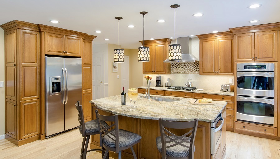 This medium kitchen feels rather large! A beautiful countertop accents the island that features curved seating, a sink and a microwave.