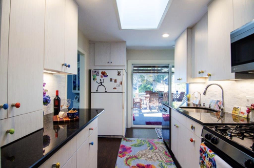 A large kitchen with stainless steel appliances. Colorful knobs makes a playful splash!