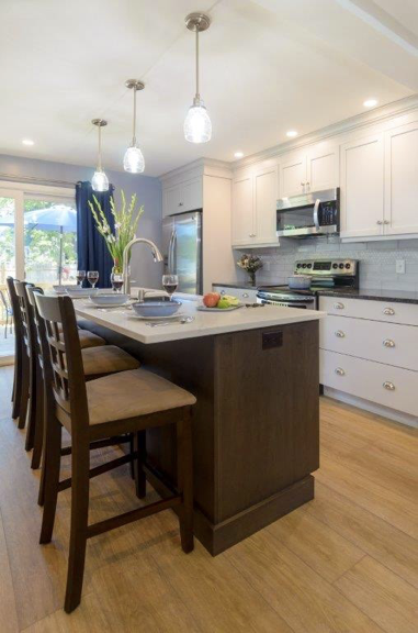 Three pendant lights hang over the island which comfortably seats four. Natural lighting flows through the large patio door. Recessed lights are an excellent choice to create the perfect mood.