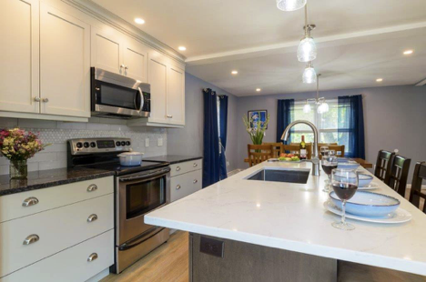 Two Tone Kitchens make a bold visual statement. White cabinets contrast black granite whereas the island features white granite against dark brown drawers. Clean crisp lines accent this kitchen. A sink installed in the island creates additional prep space by the oven and stove. 