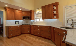 Warm wood cabinets create a relaxing atmosphere. Recessed lighting accents this kitchen by creating the perfect mood.