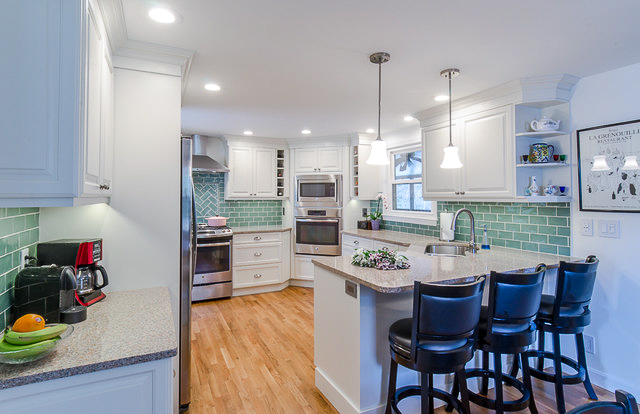This is a medium white kitchen with a mint green backsplash. 